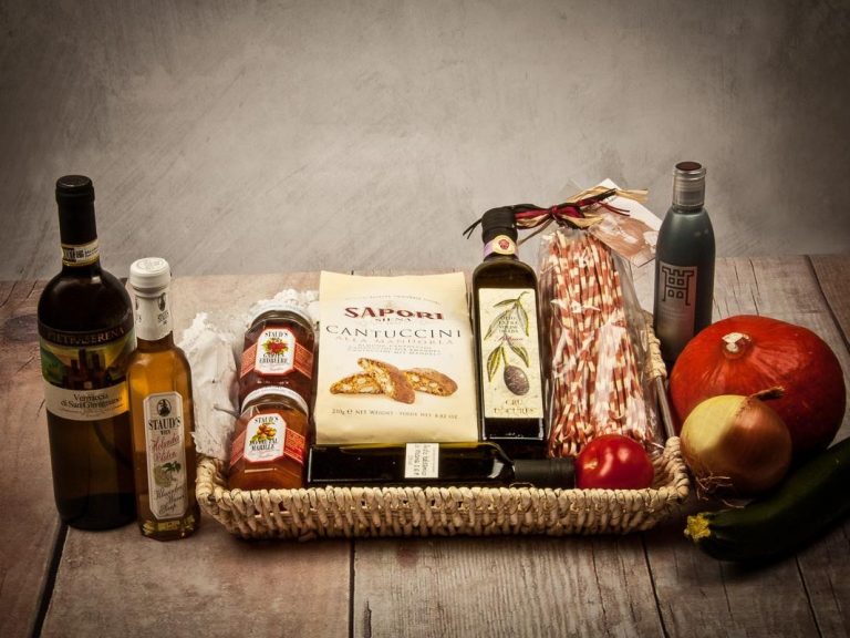 Korb mit Wein, Olivenöl, Wurst, Brot, Marmelade, Obst und Gemüse.