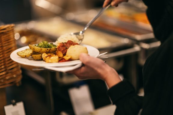 Ein Teller mit vielseitigem Essen, darunter Kartoffeln, Gemüse und Sauce.